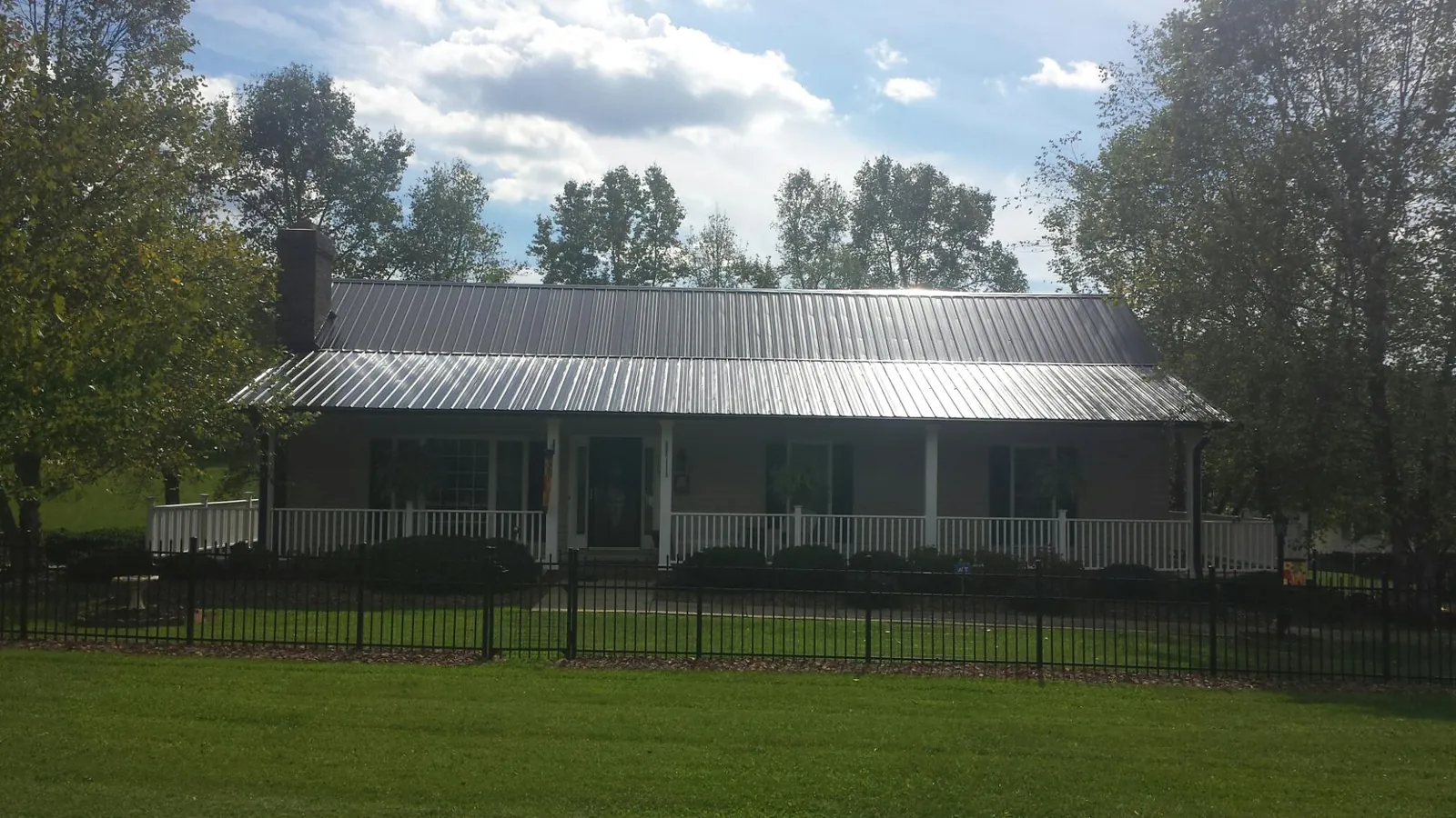 Gray metal roof on a brick ranch with a full width front porch — Gutter Guard Installation work by our crew in Trumbauersville