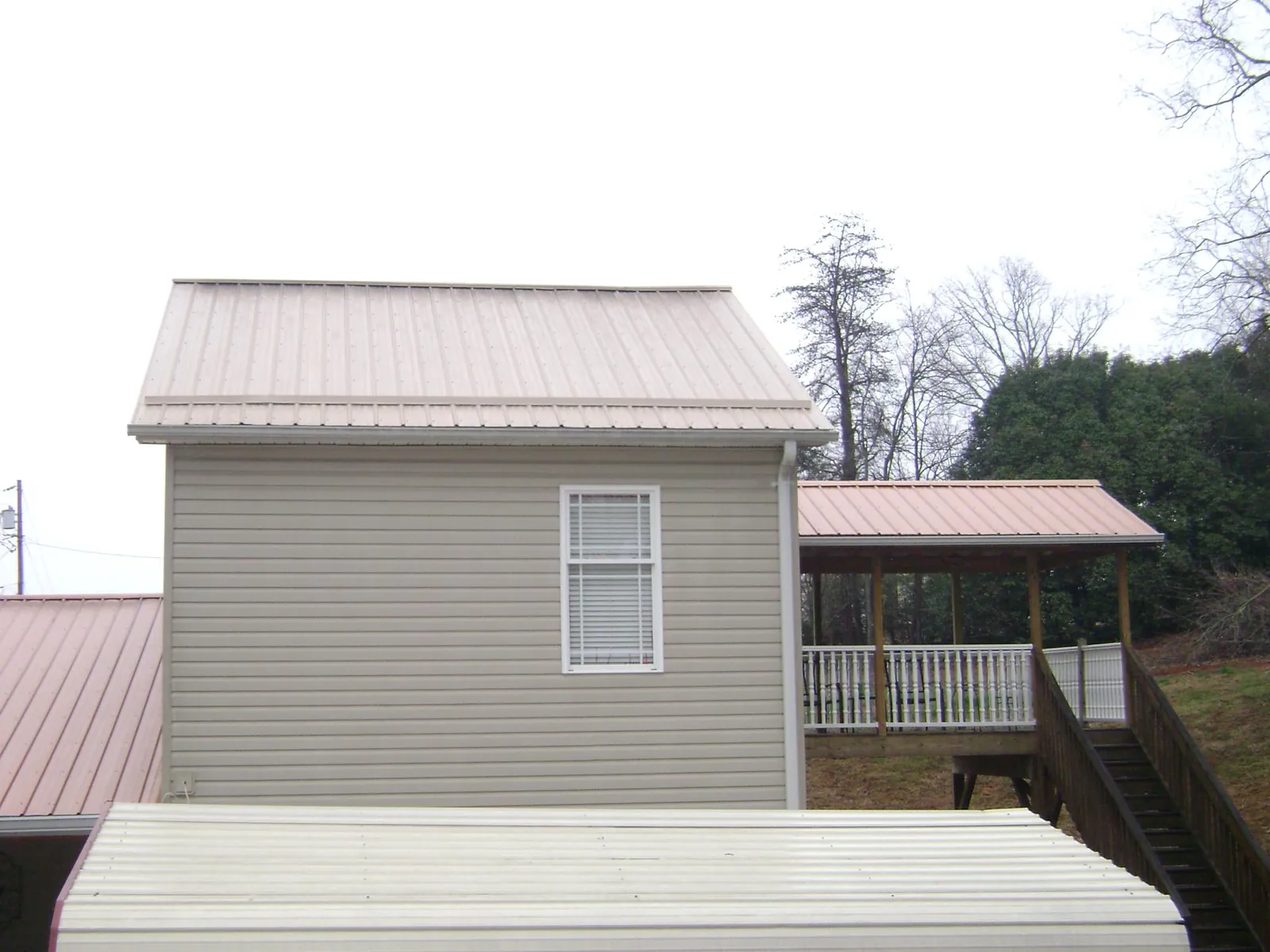 Tan metal roofs on a two story addition and attached porch, from a Roof Replacement job in Trumbauersville