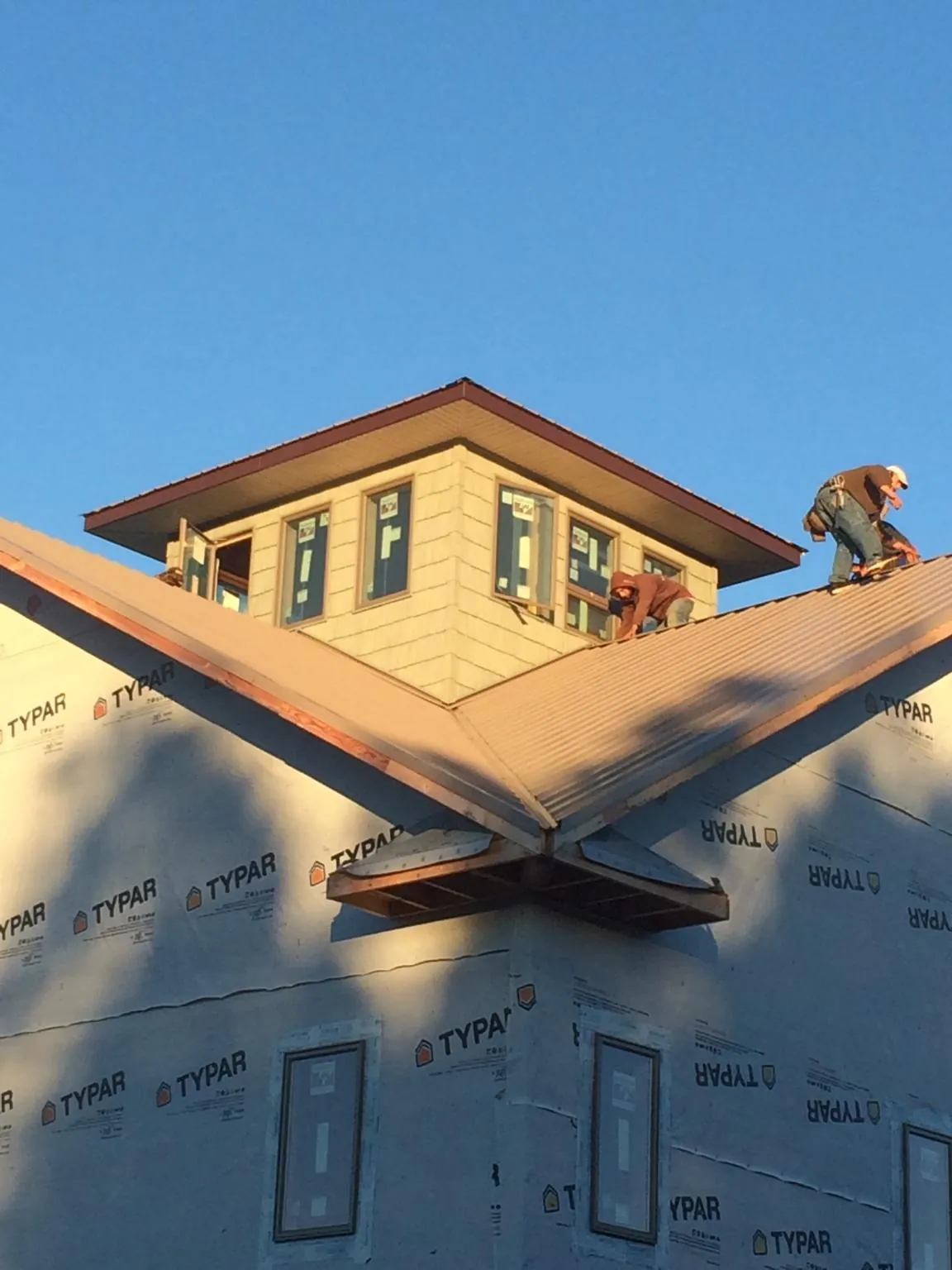 Roofers working around a rooftop cupola on a new metal roof at sunset — Roof Waterproofing in Trumbauersville by Roofing Brothers